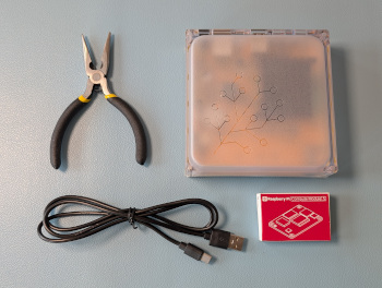 Image showing the Home Assistant Yellow, a Raspberry Pi Compute Module 5, Ethernet cable, power supply, a USB-C cable, and flat-nose pliers